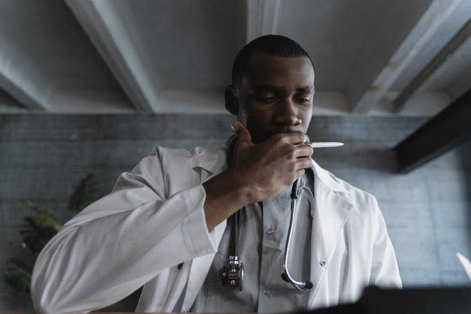 A Man with Stethoscope Around Neck Covering Mouth with his Hand